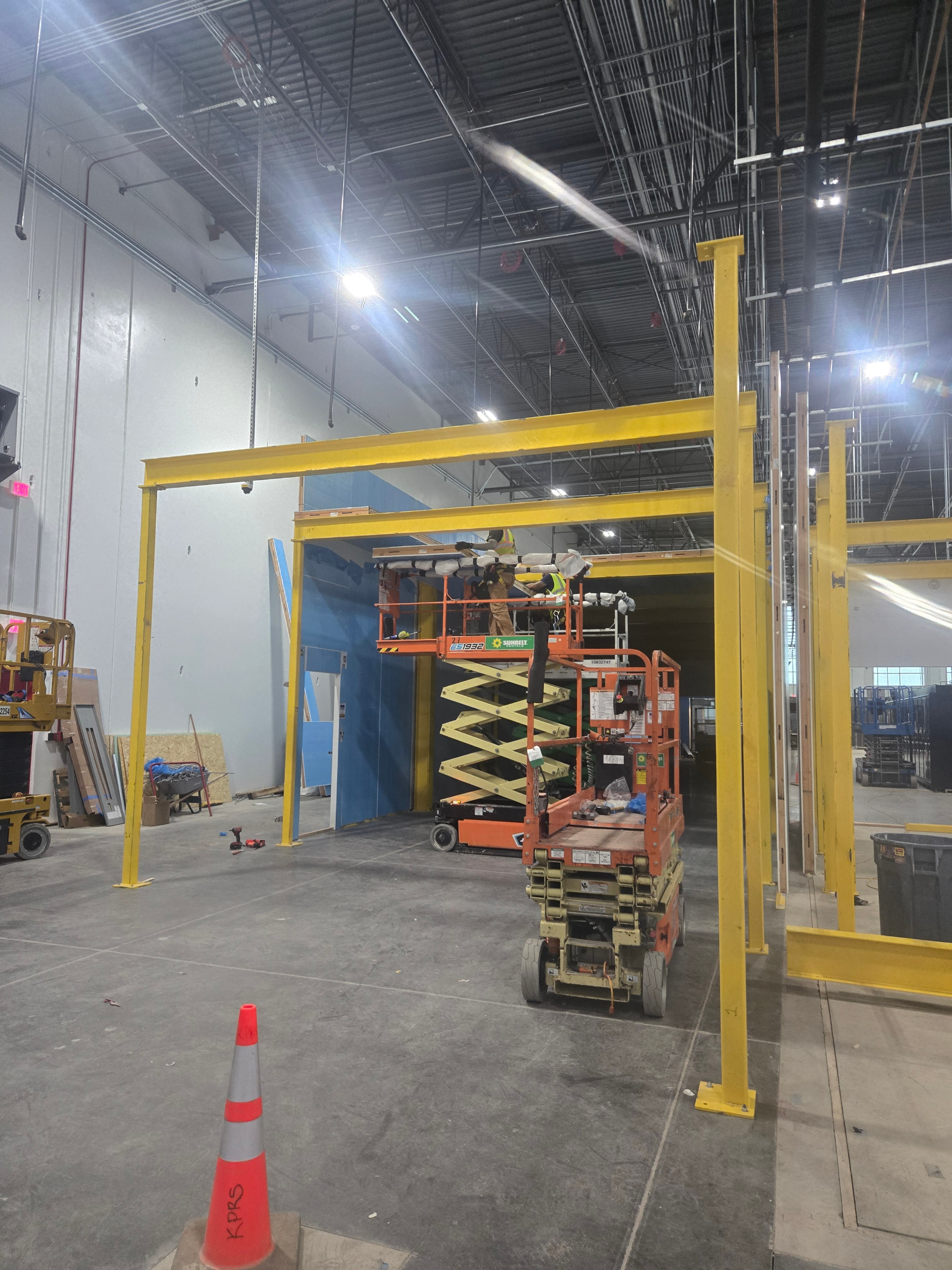Yellow structural frame of walk-in cooler being assembled inside Amazon warehouse