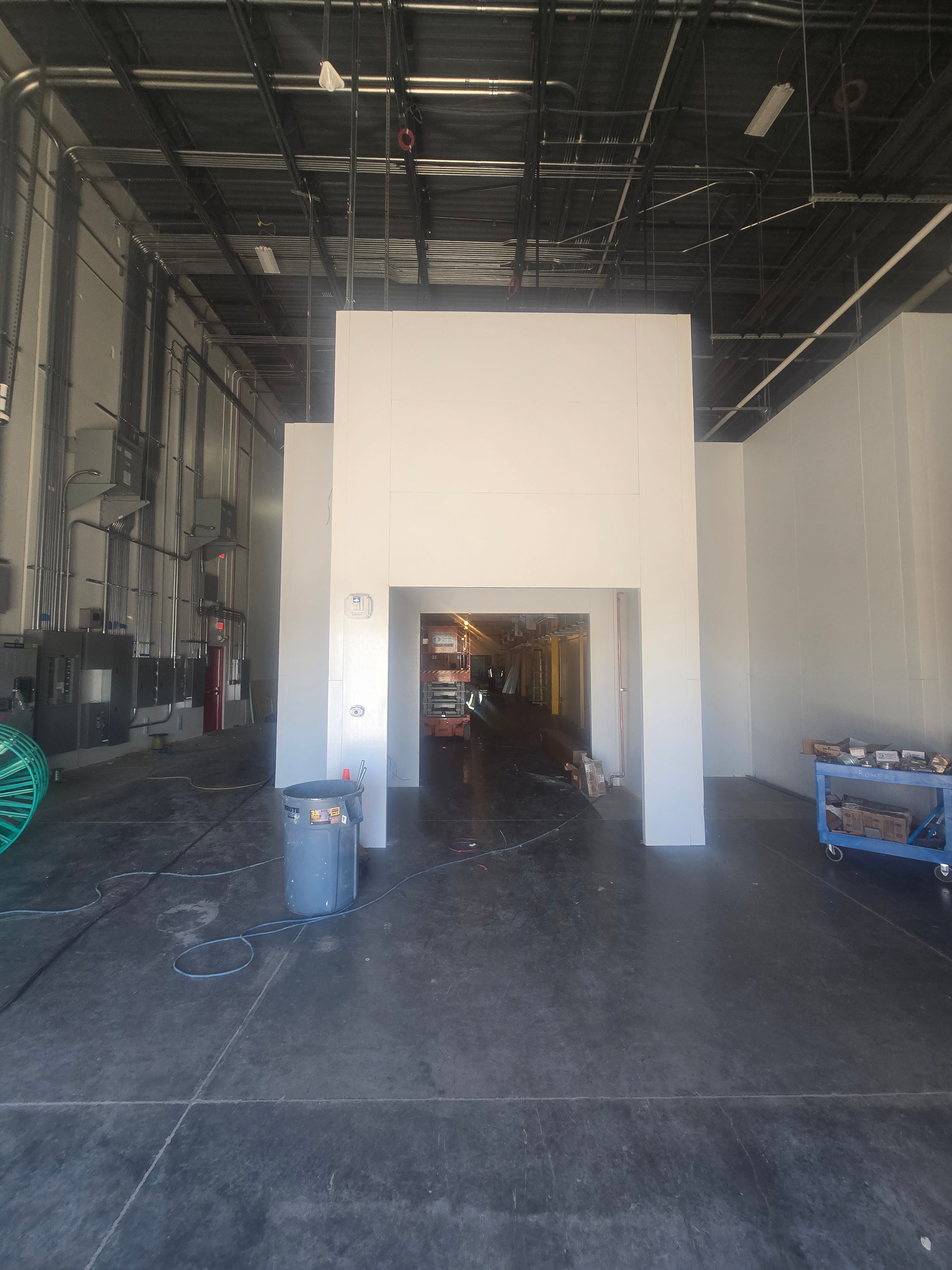 Completed white walk-in cooler exterior panel wall with door opening inside Amazon warehouse