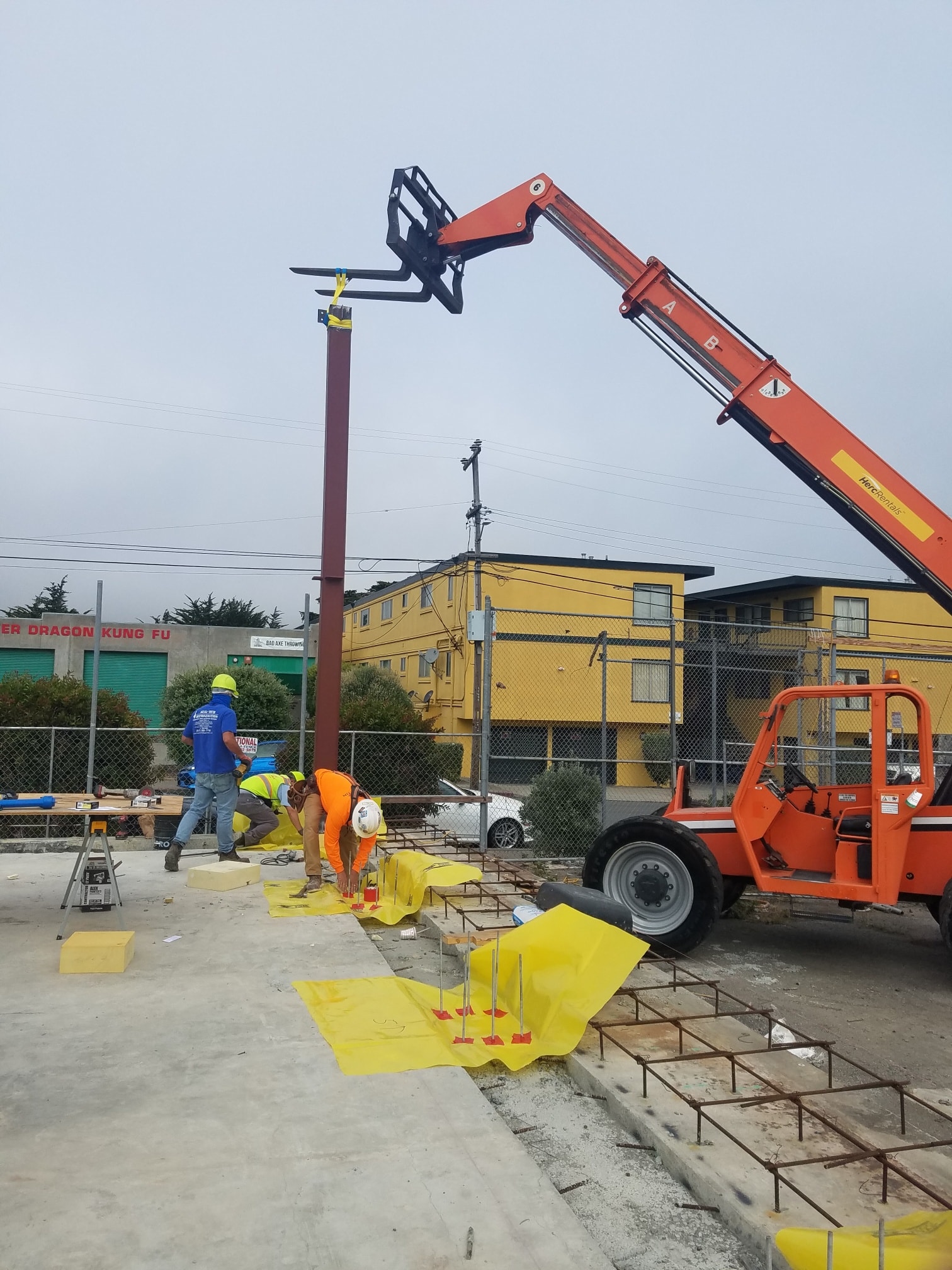 Workers installing warehouse structural steel with a telehandler